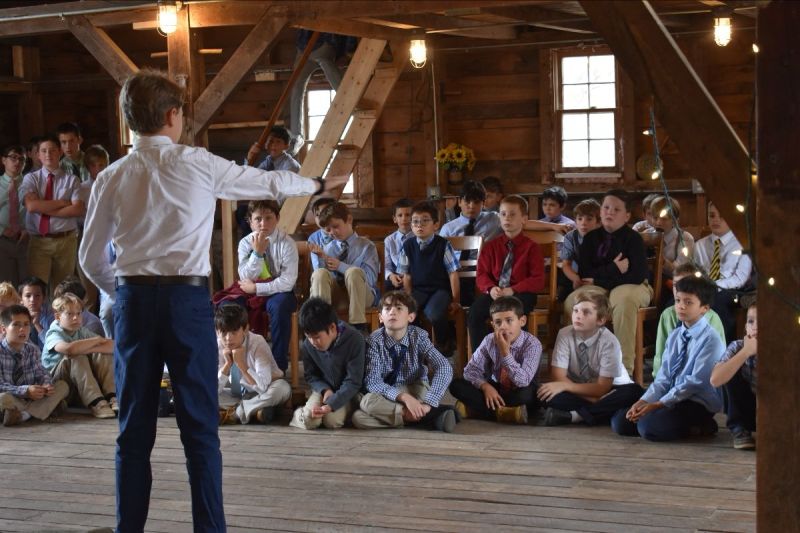 Boys siting inside a barn