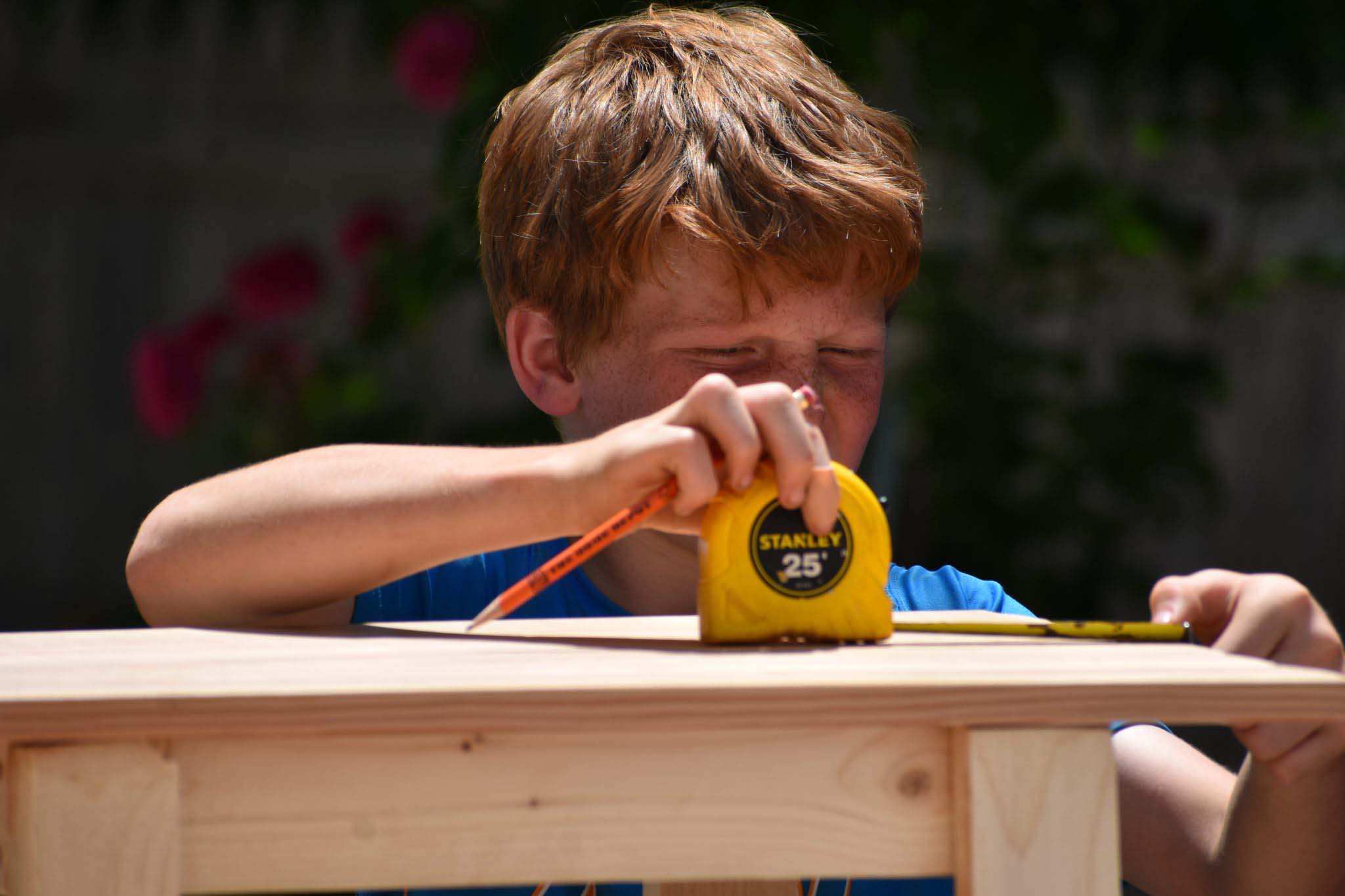 Boy using tapemeasure on table
