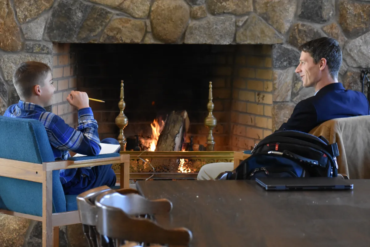 Teacher mentors a student by the fireplace