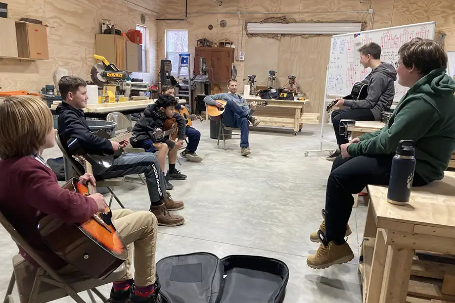 Students and teacher playing guitar