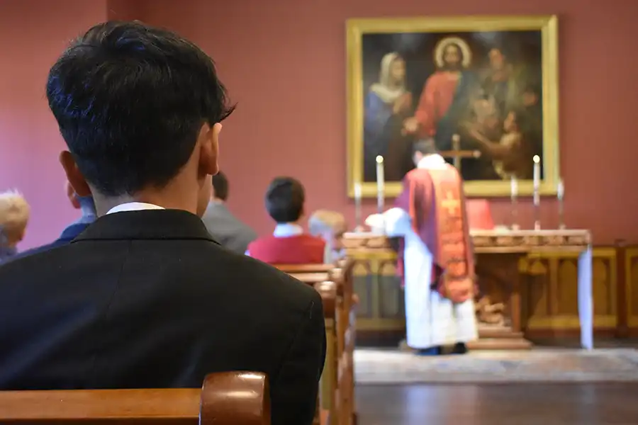 Male student in chapel during Mass