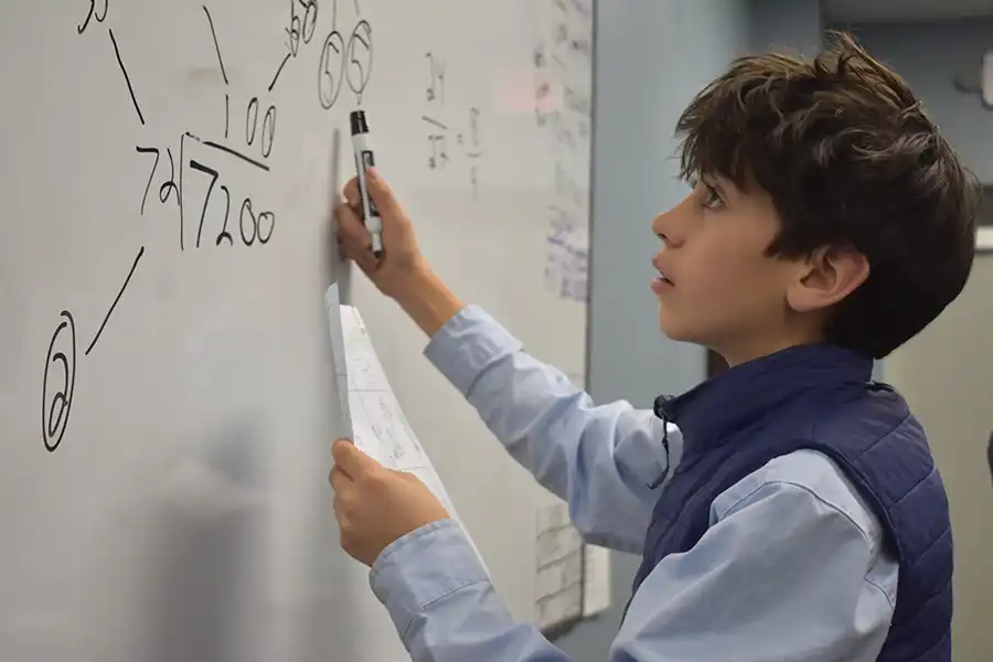 Boy in math club doing a problem on the board