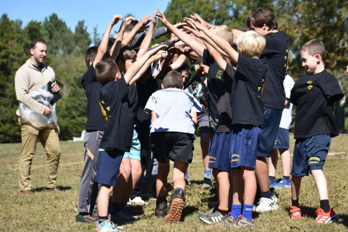 Boys outside running under group of hands, rallying together