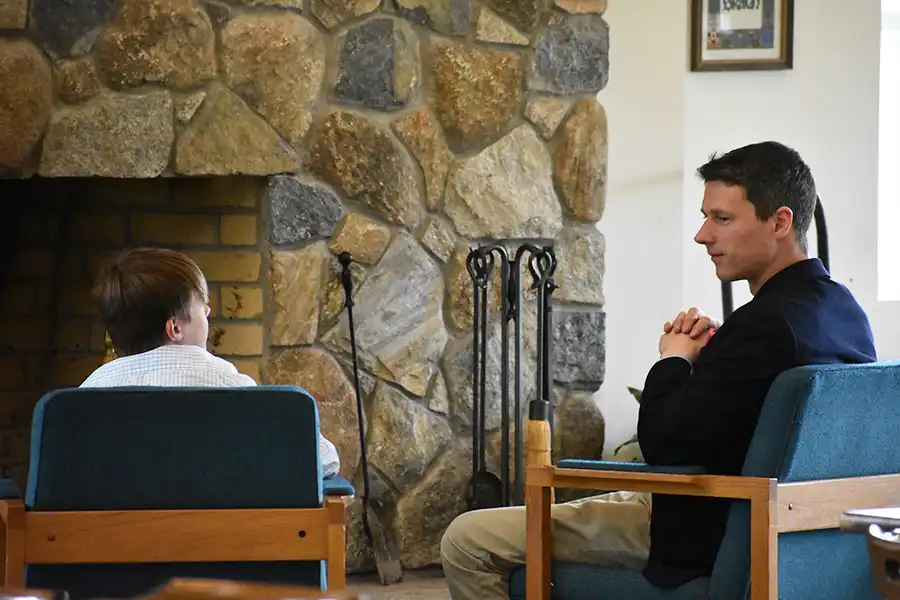 Sparhawk teacher mentoring student by fireplace